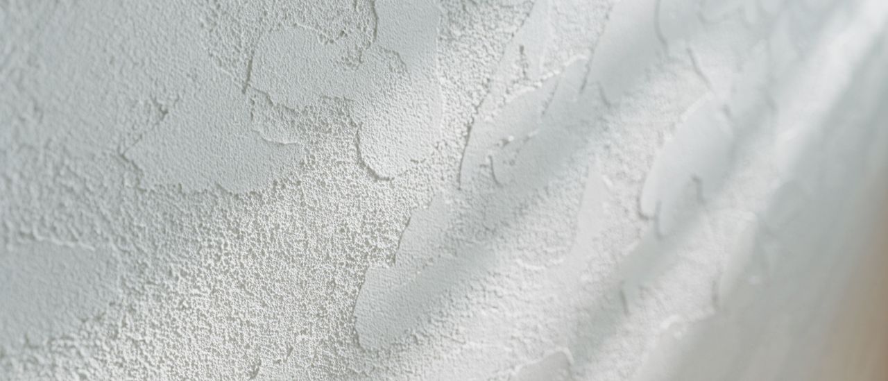Detail of a knockdown ceiling texture showing flattened mottled plaster