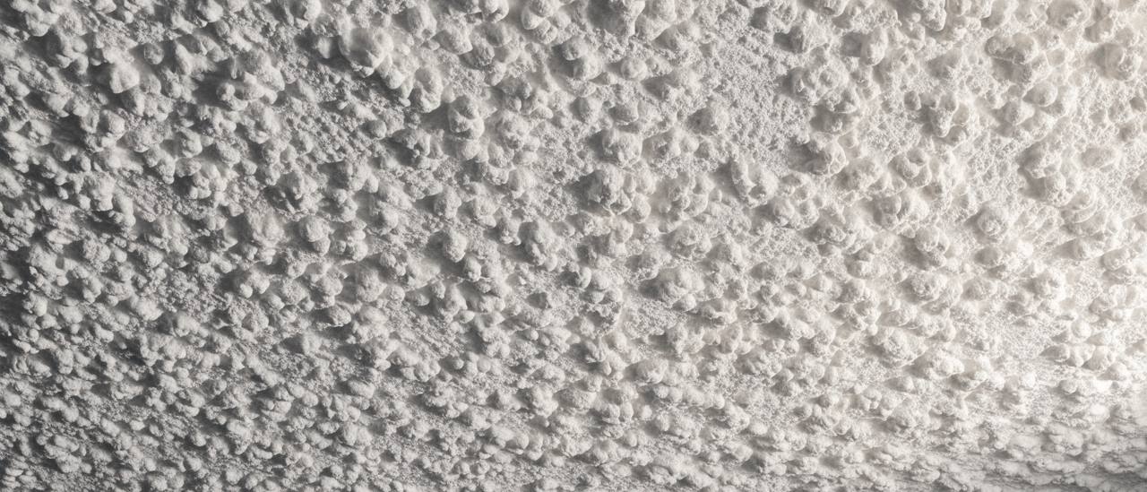 Close-up of white popcorn ceiling texture showing its rough peaked surface