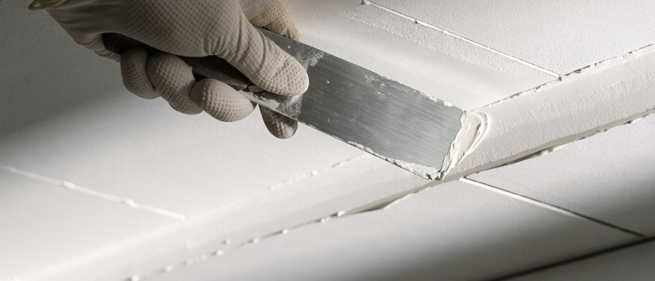 Drywall compound being floated over a repaired ceiling seam with a wide taping knife